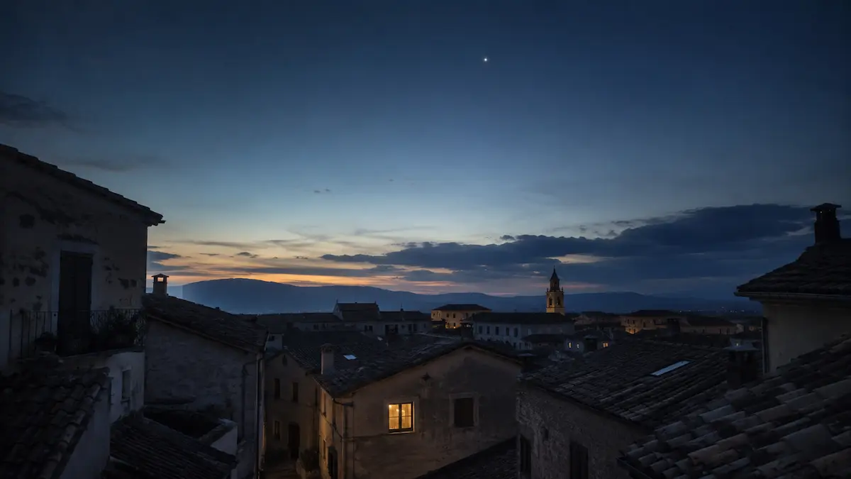 un piccolo paese al crepuscolo, visto dall’alto dei tetti, con un cielo ancora profondo e una sola stella chiaramente visibile